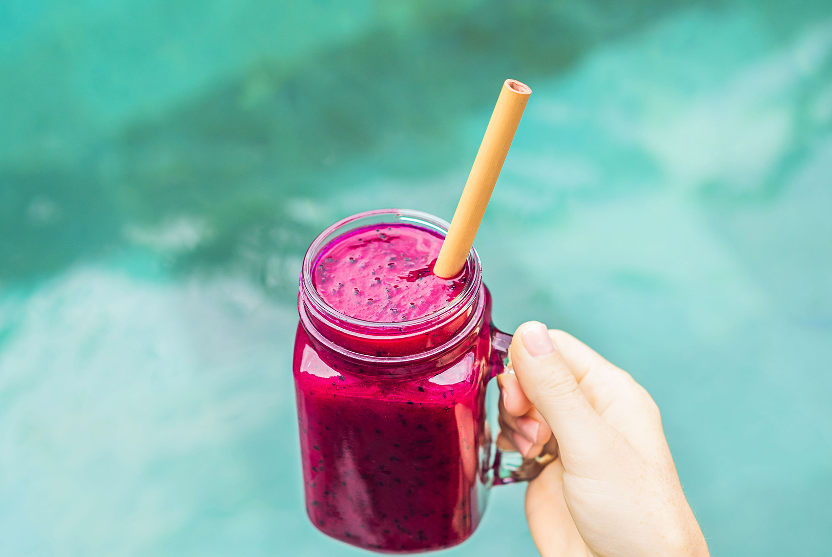 Pineapple and dragon fruit purple smoothie in a mason jar with a bamboo straw.