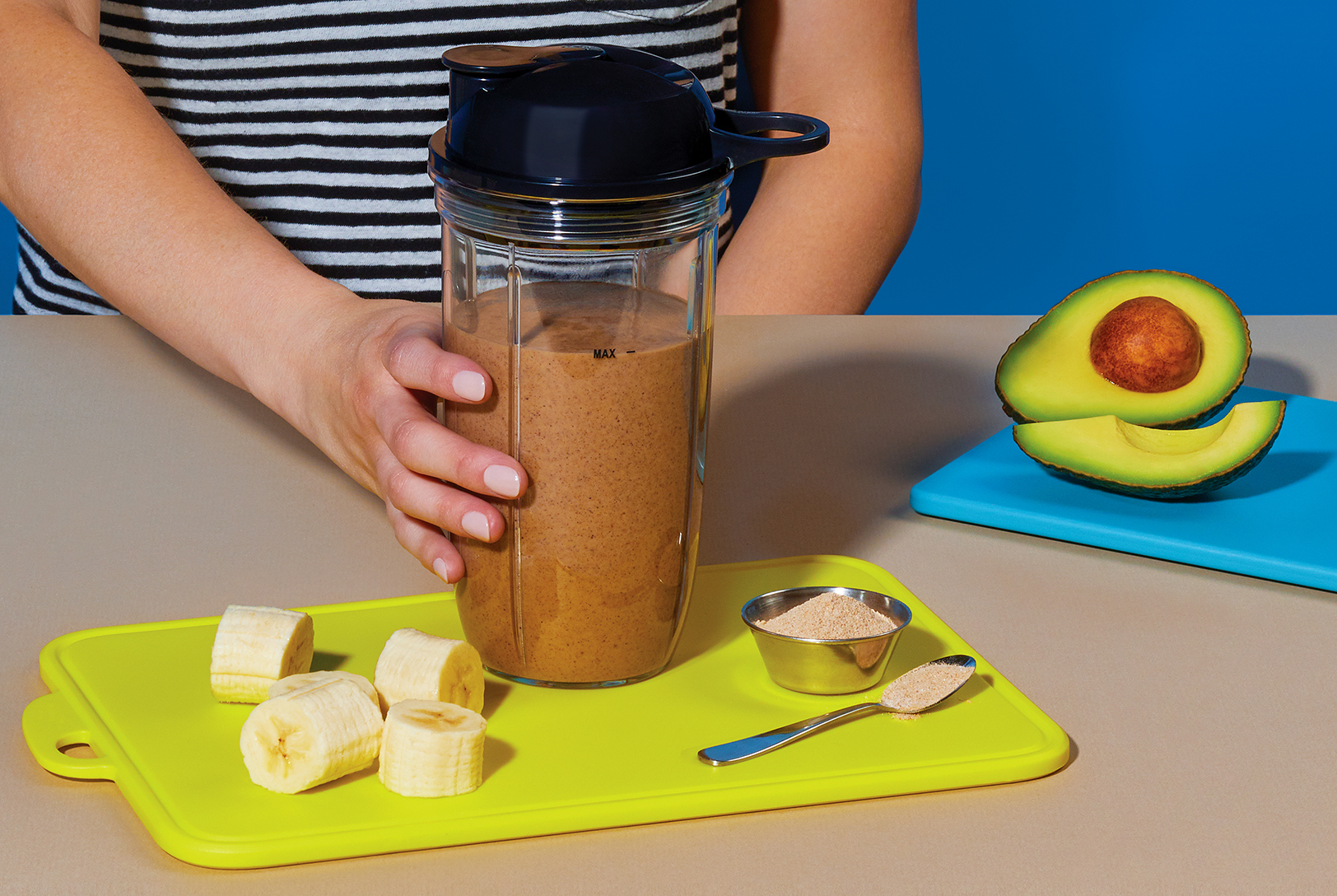 chocolate protein post-workout shake next to avocado, sliced banana and protein powder