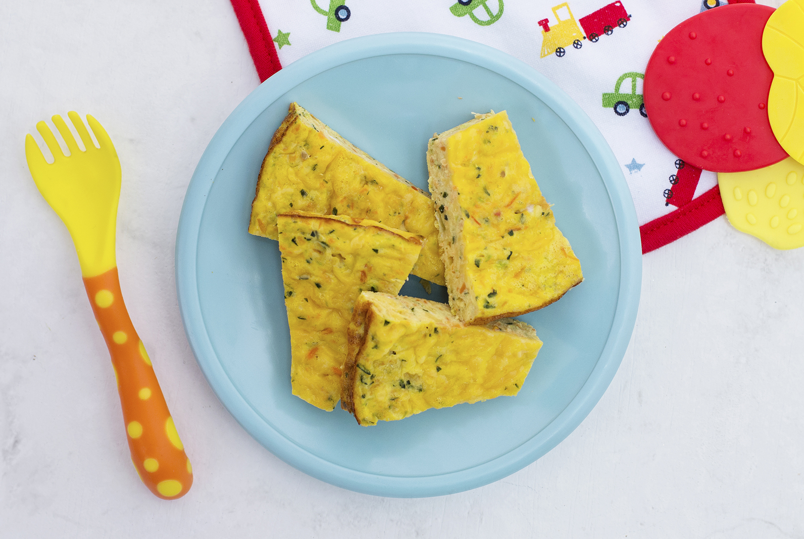 Four slices of Veggie Frittata on a light blue plate, next to a yellow and orange baby fork with polka dots.