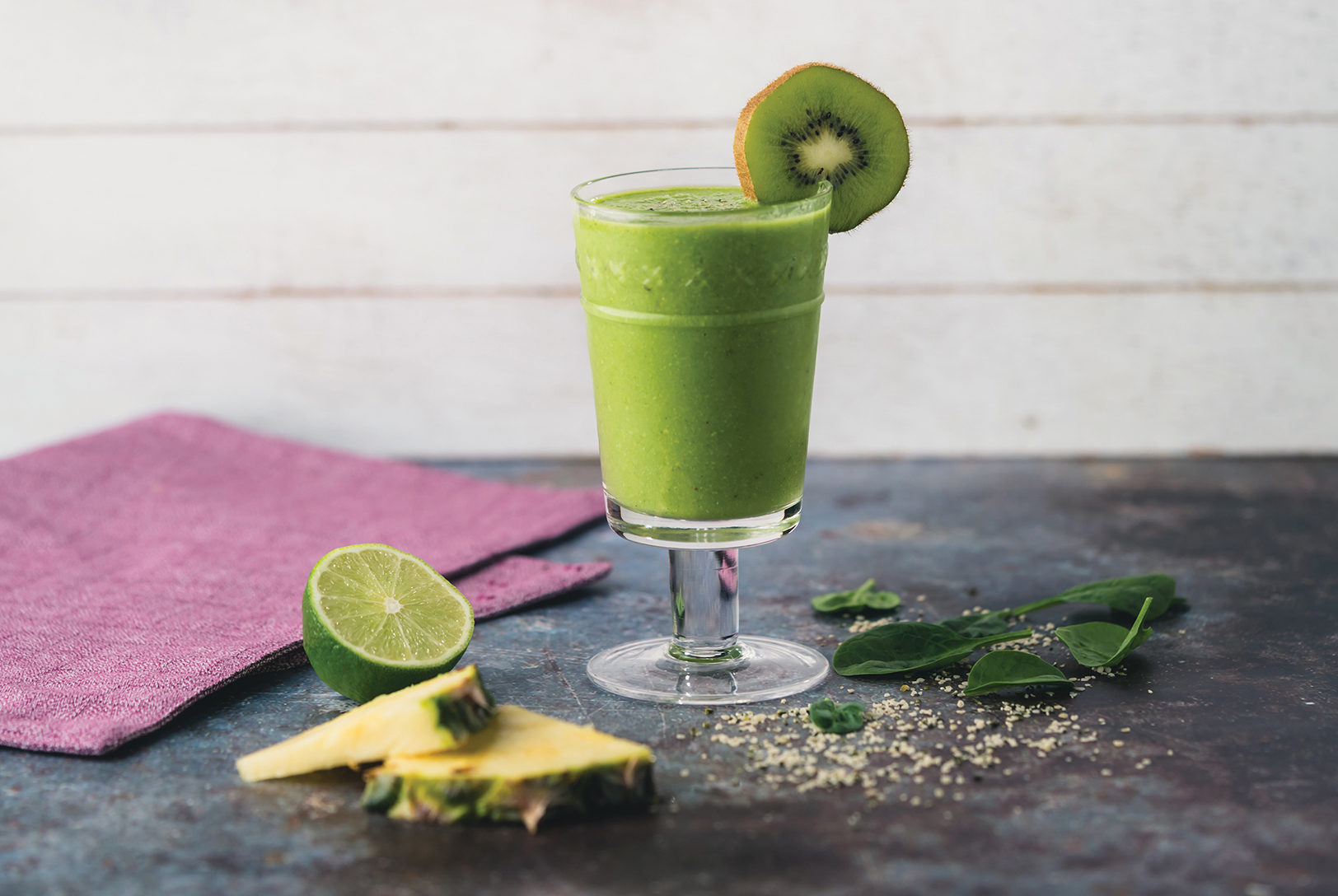 cup of tropical green smoothie with kiwi, pineapple, lime and mini umbrella 