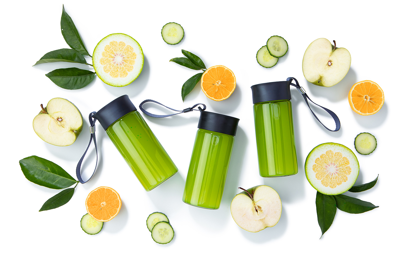 three bottles of green juice with apples cucumber and oranges