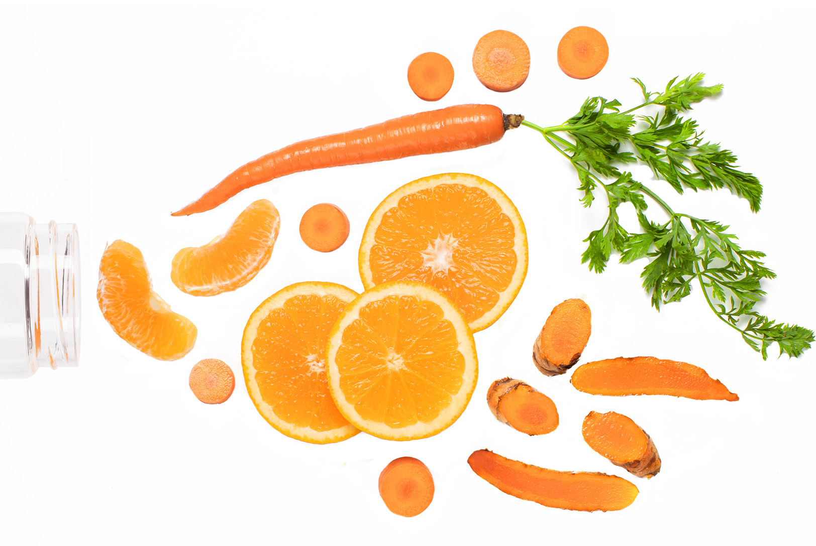 orange slices, carrots, and turmeric going into mouth of jar