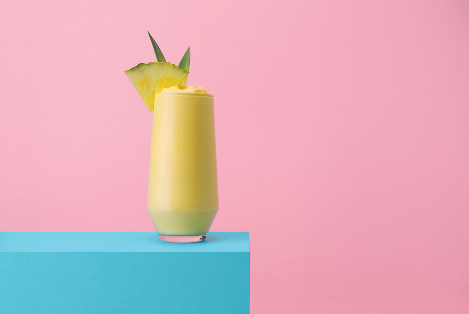 glass of blended pina colada cocktail with pineapple slice
