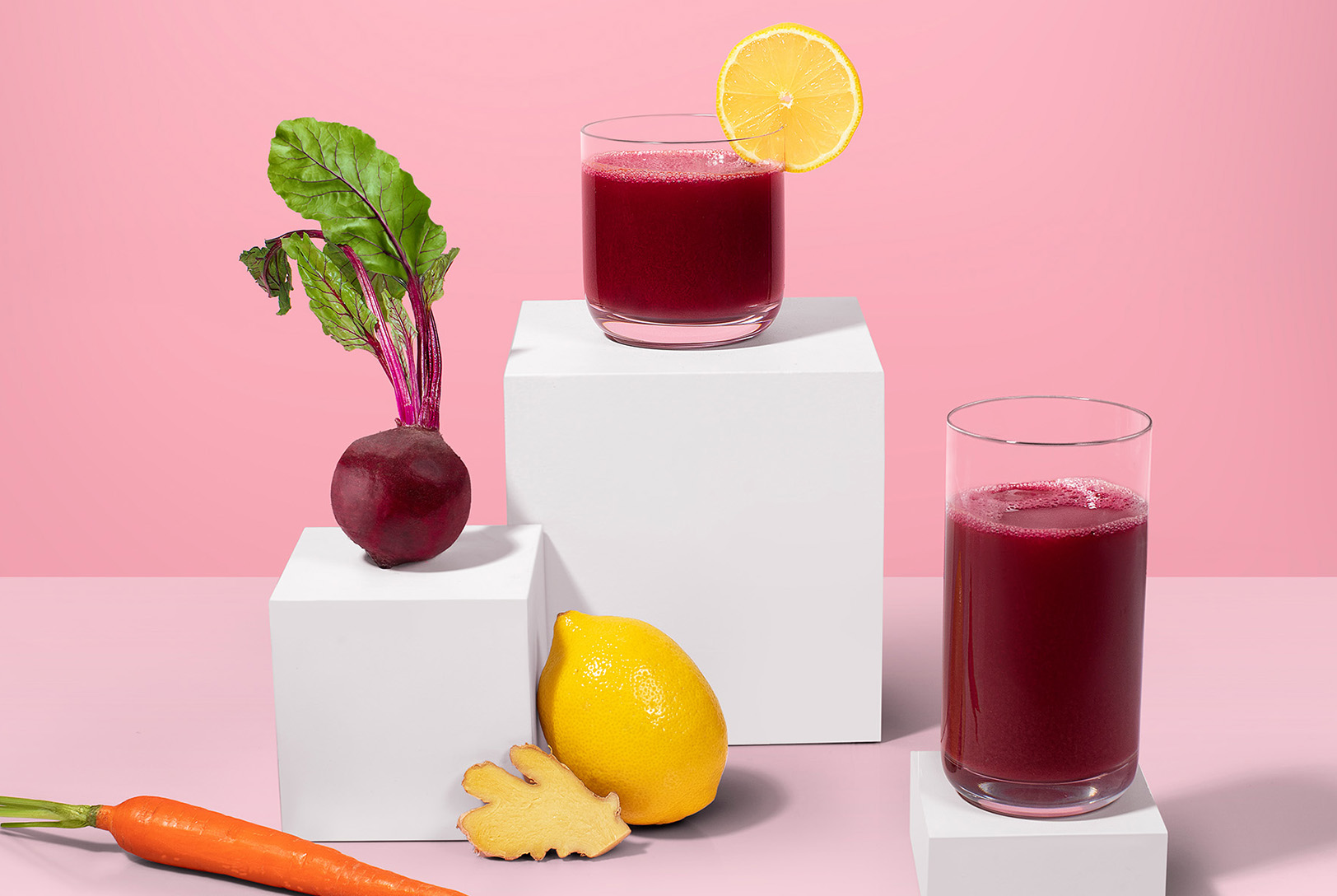 glasses of beet juice with beet, lemon, ginger, and carrot