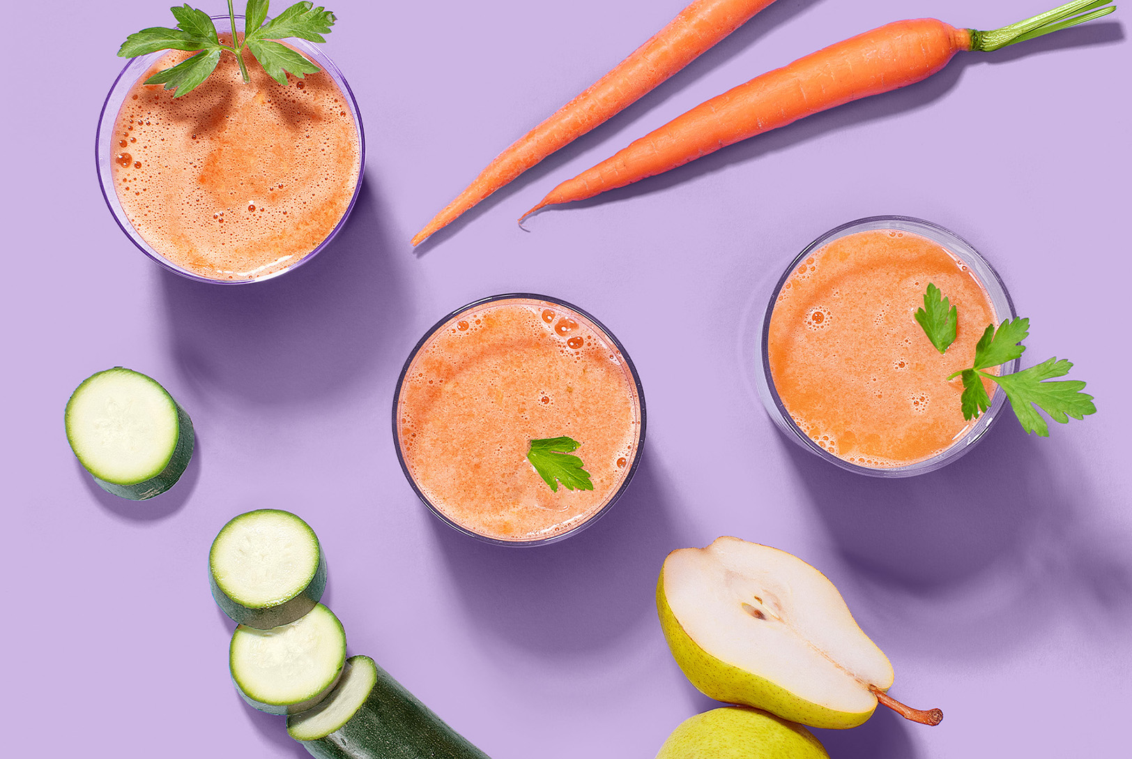 glasses of carrot juice with carrots, pears, and zucchini