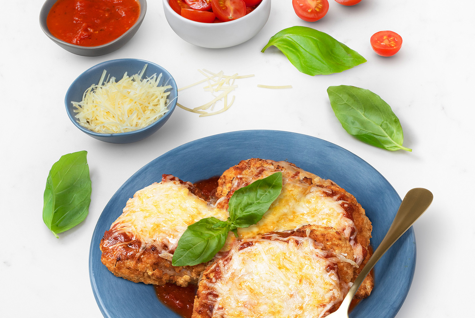 plate of chicken parmesan with basil and cherry tomatoes