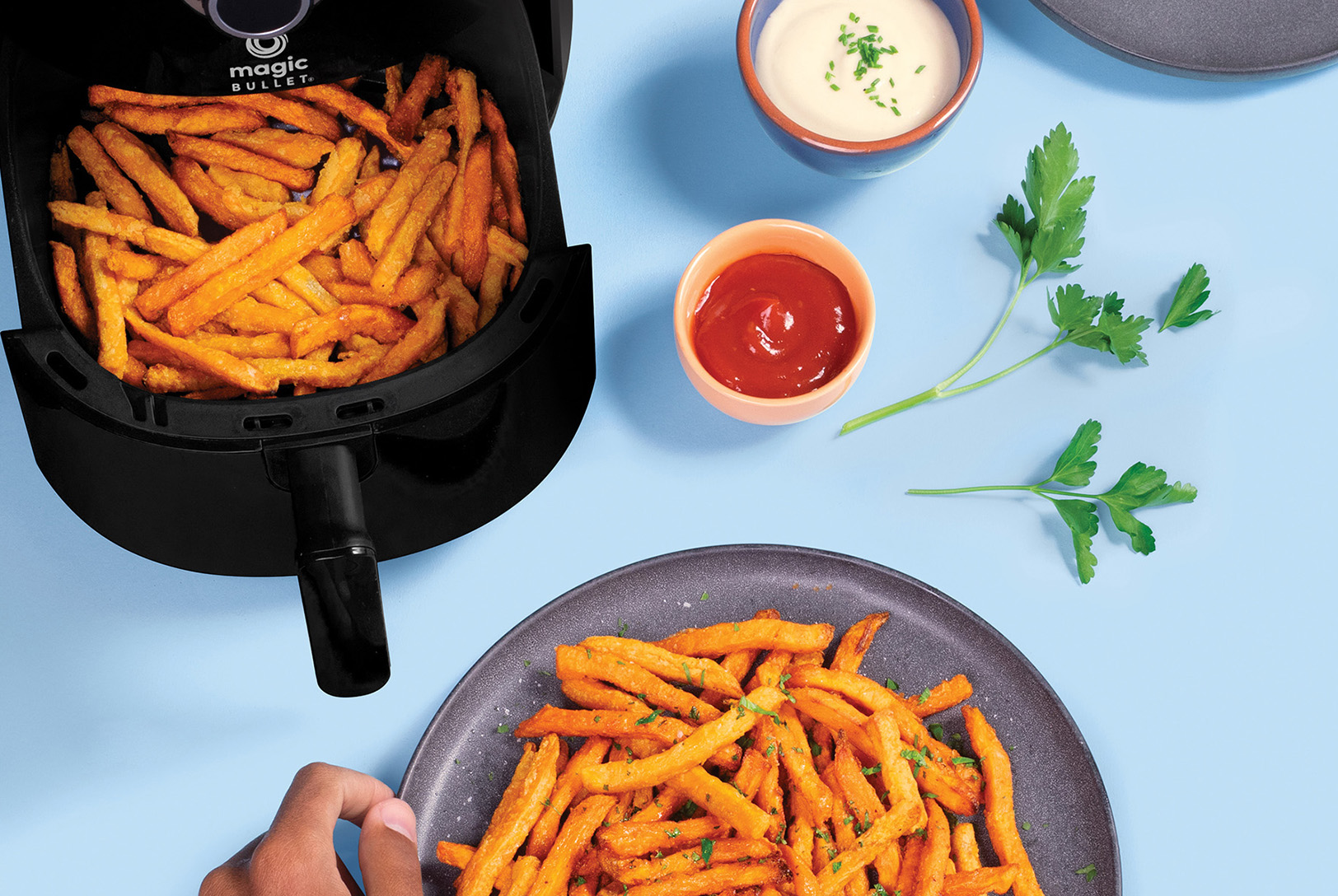 plate of sweet potato fries fresh from air fryer with aioli and ketchup
