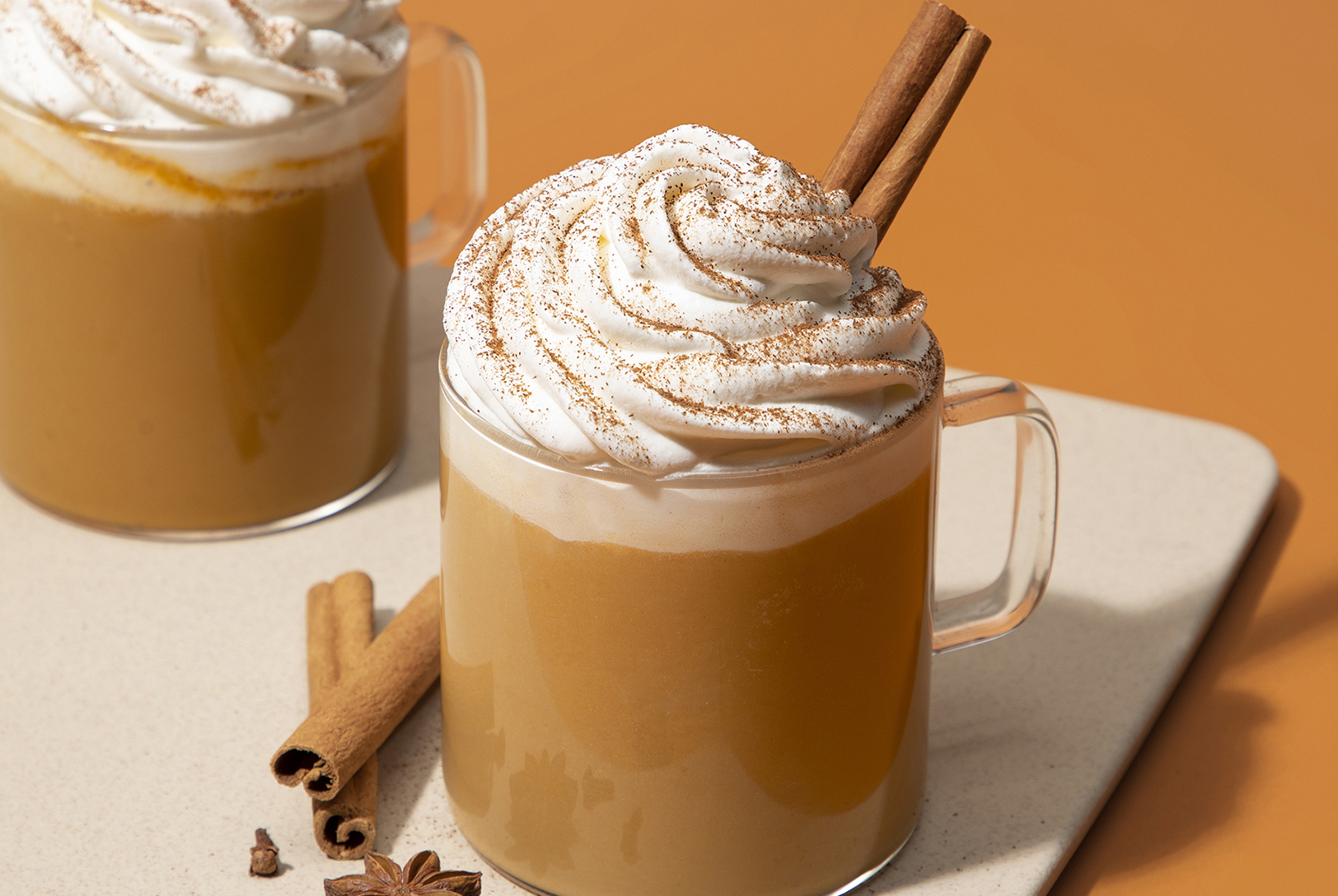 glass mug of pumpkin spiced latte with whipped cream and cinnamon