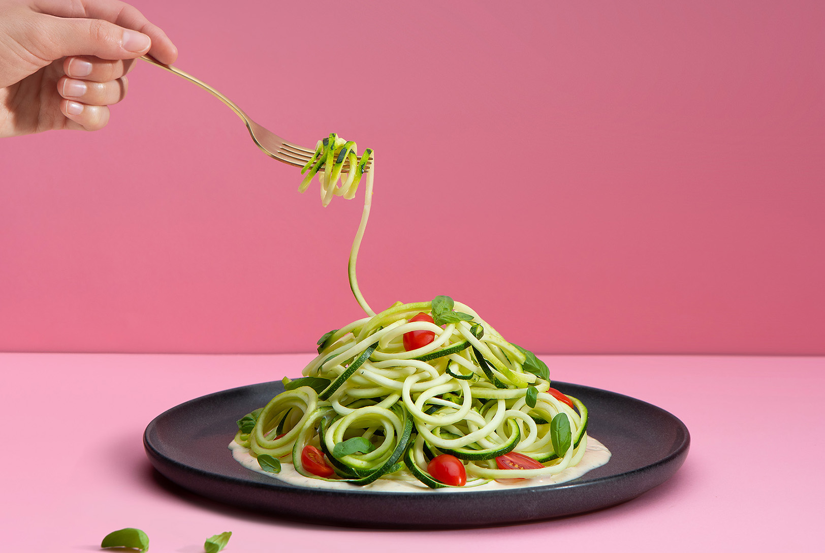 plate of zucchini noodles with cashew cream sauce, basil and cherry tomatoes