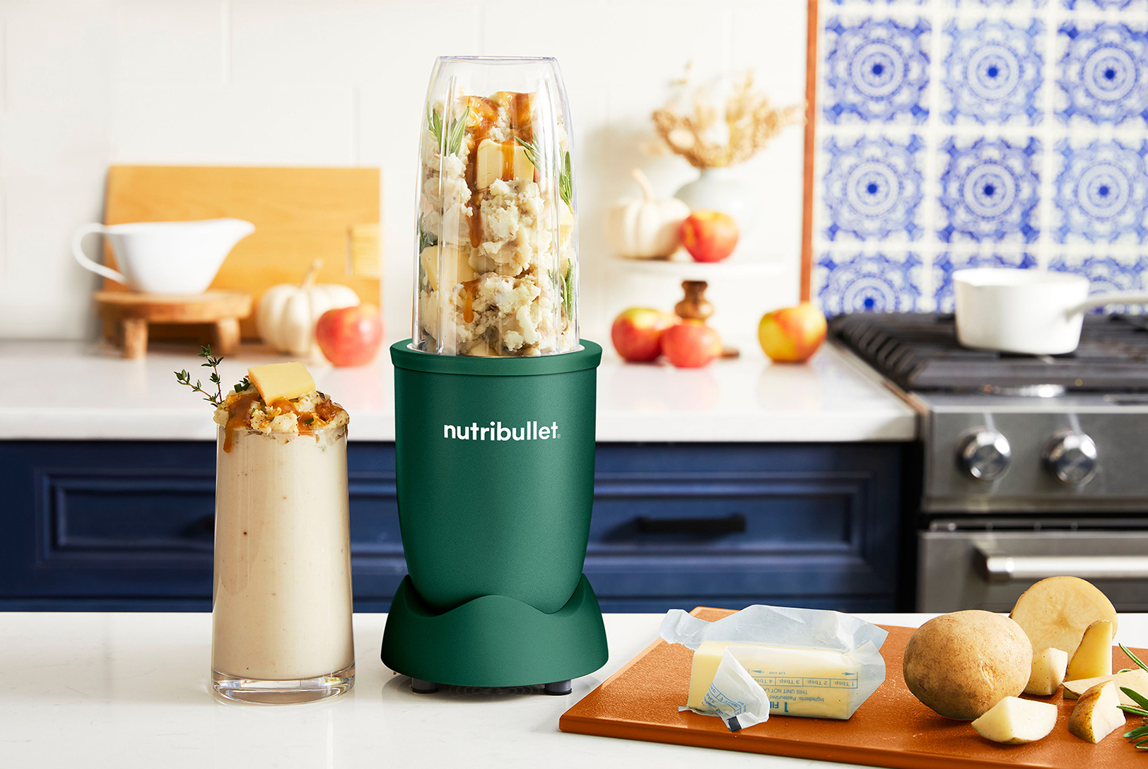 glass of blended mashed potatoes with a green nutribullet blender next to butter and potatoes