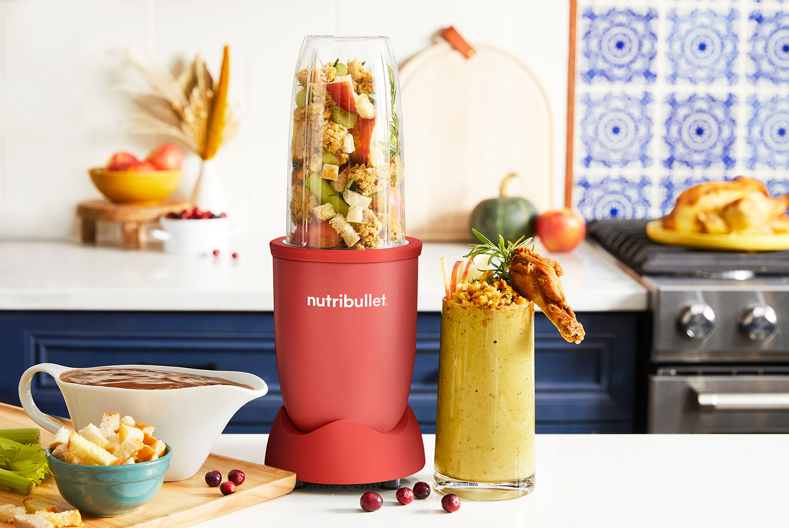 Gravy boat next to a burgundy nutribullet blender filled with stuffing along with a cup of blended stuffing