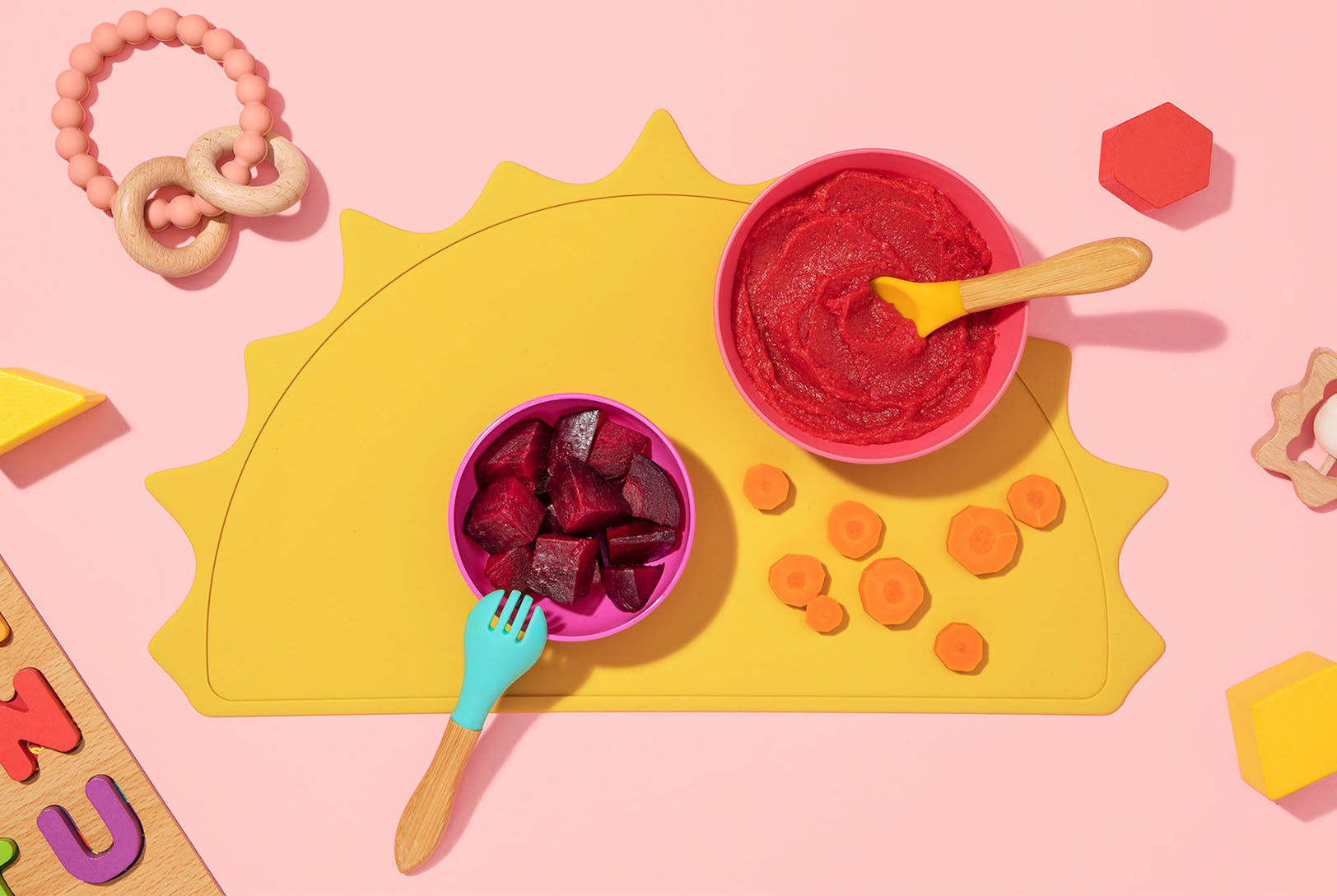 two bowls of beets, pureed and chopped with utensils and toys