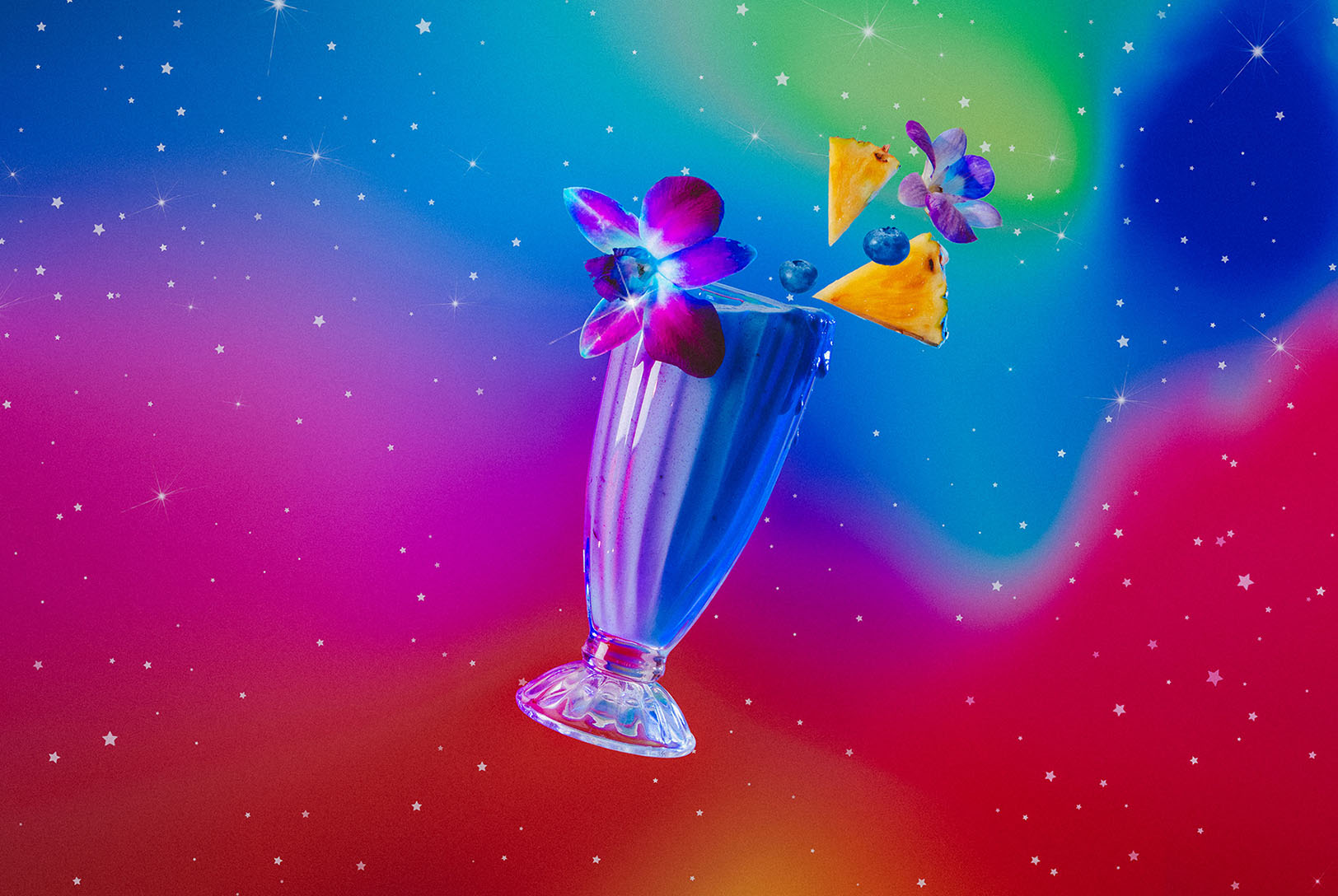 Pisces zodiac inspired sweet, creamy, blue cocktail with floating flowers and pineapple garnish in cosmic surroundings