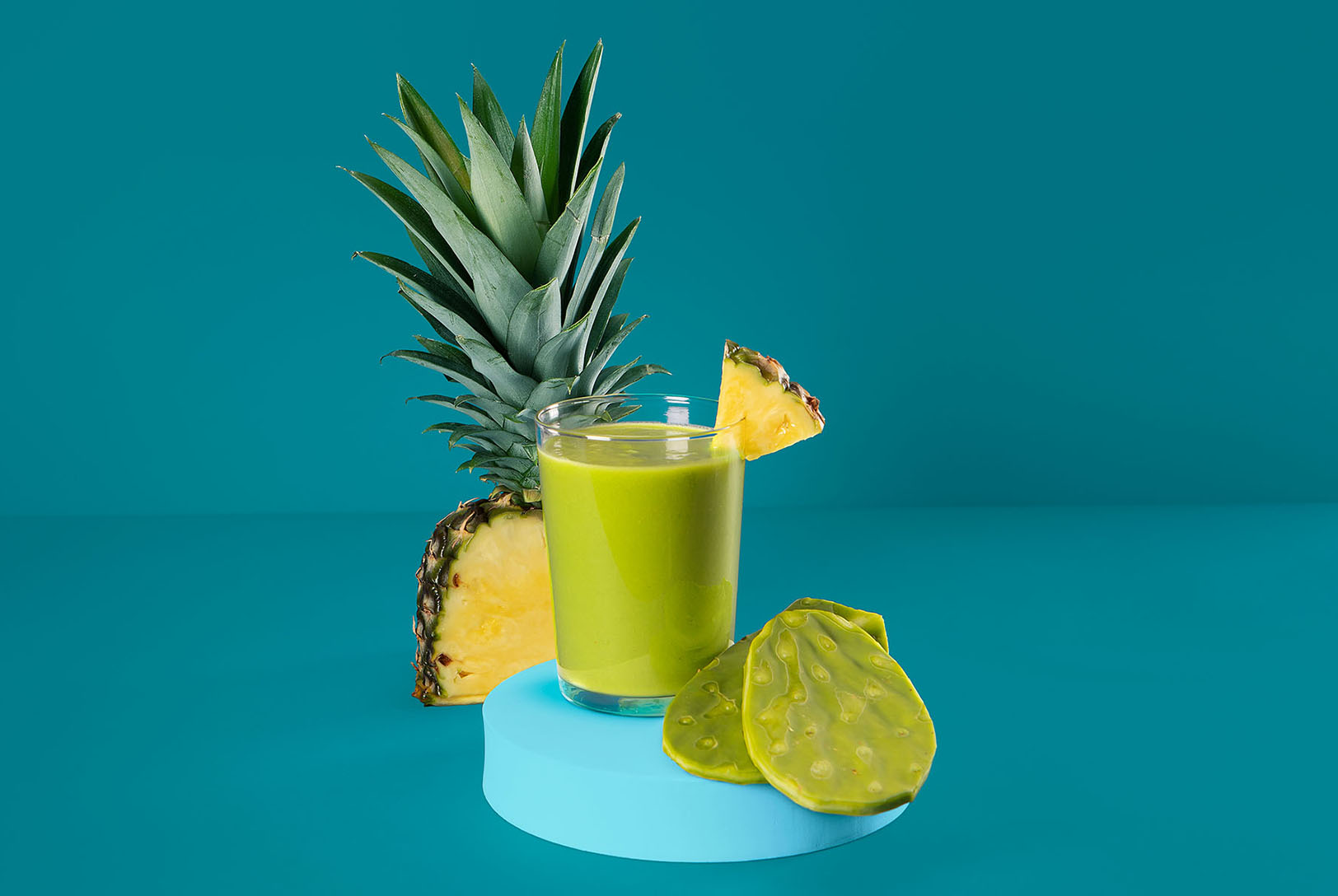 green smoothie garnished with fresh pineapple and cactus