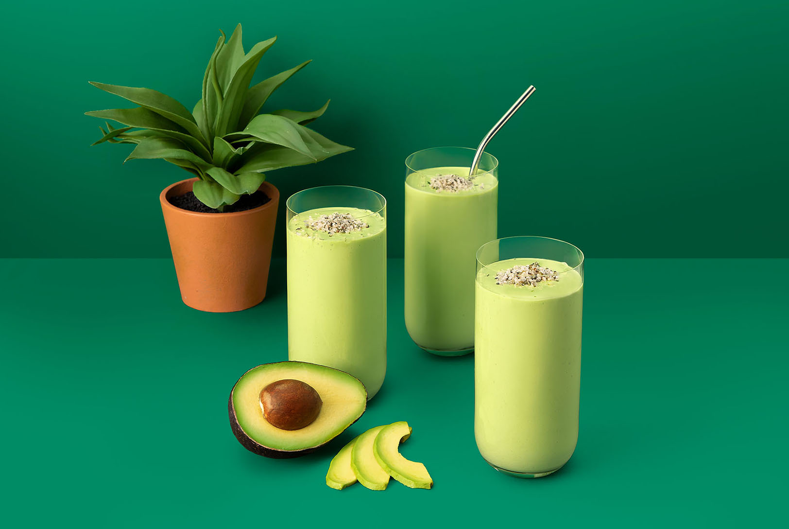 Green smoothie in glasses topped with hemp seeds on green background