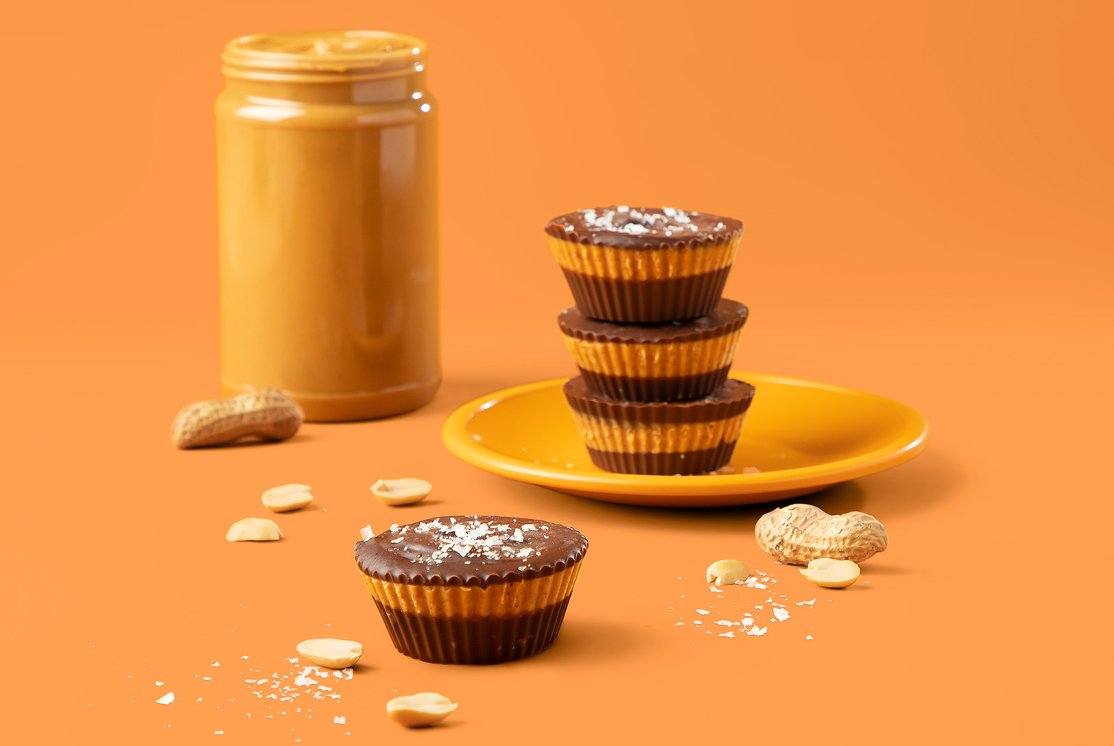 stack of homemade nut and seed butter cups with jar of peanut butter 