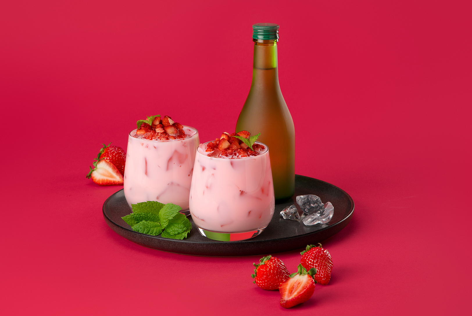 two glasses of pink cocktail with strawberries, mint, and ice